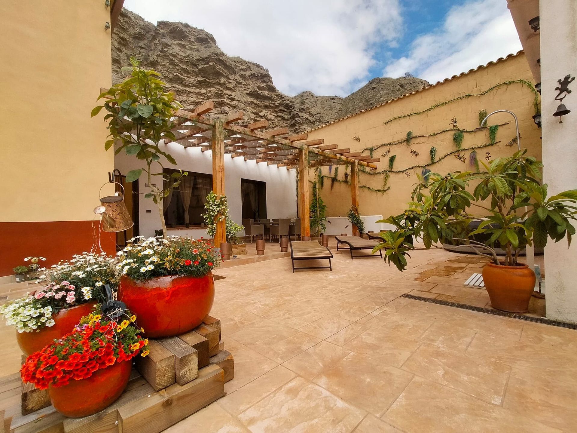 Un patio con muchas plantas en macetas y una pérgola.
