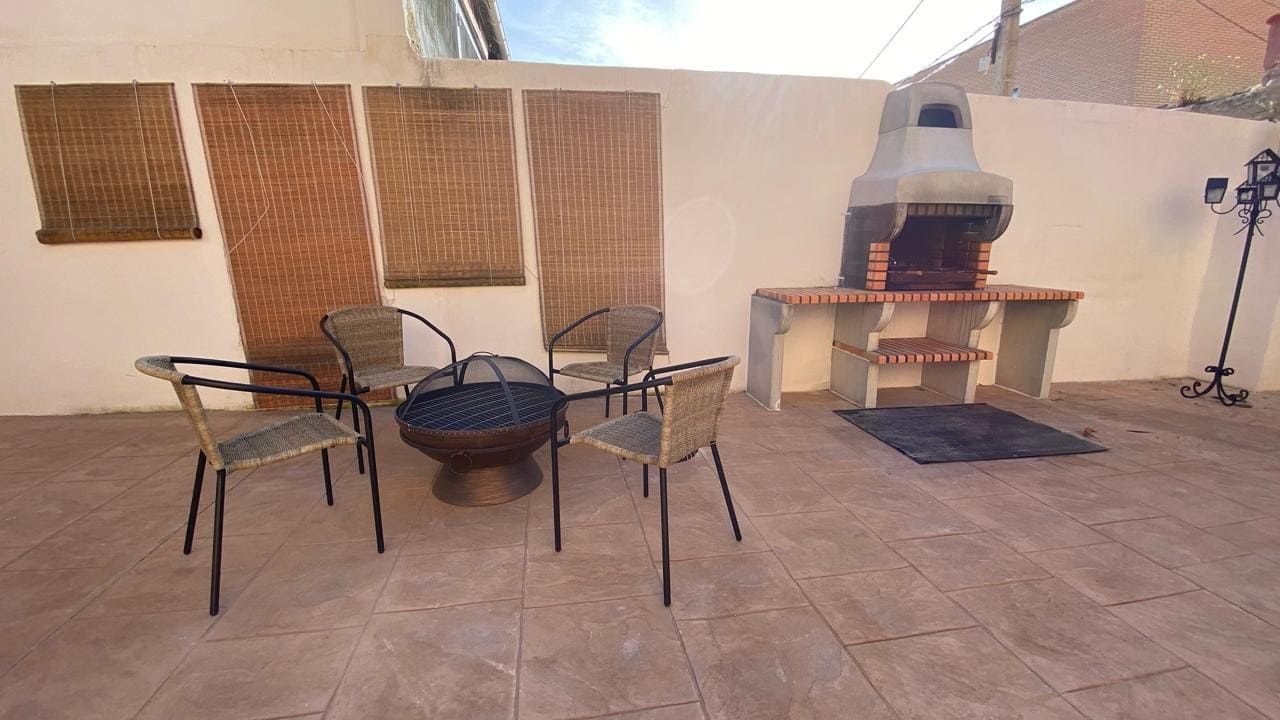 Un patio con mesa y sillas y parrilla.