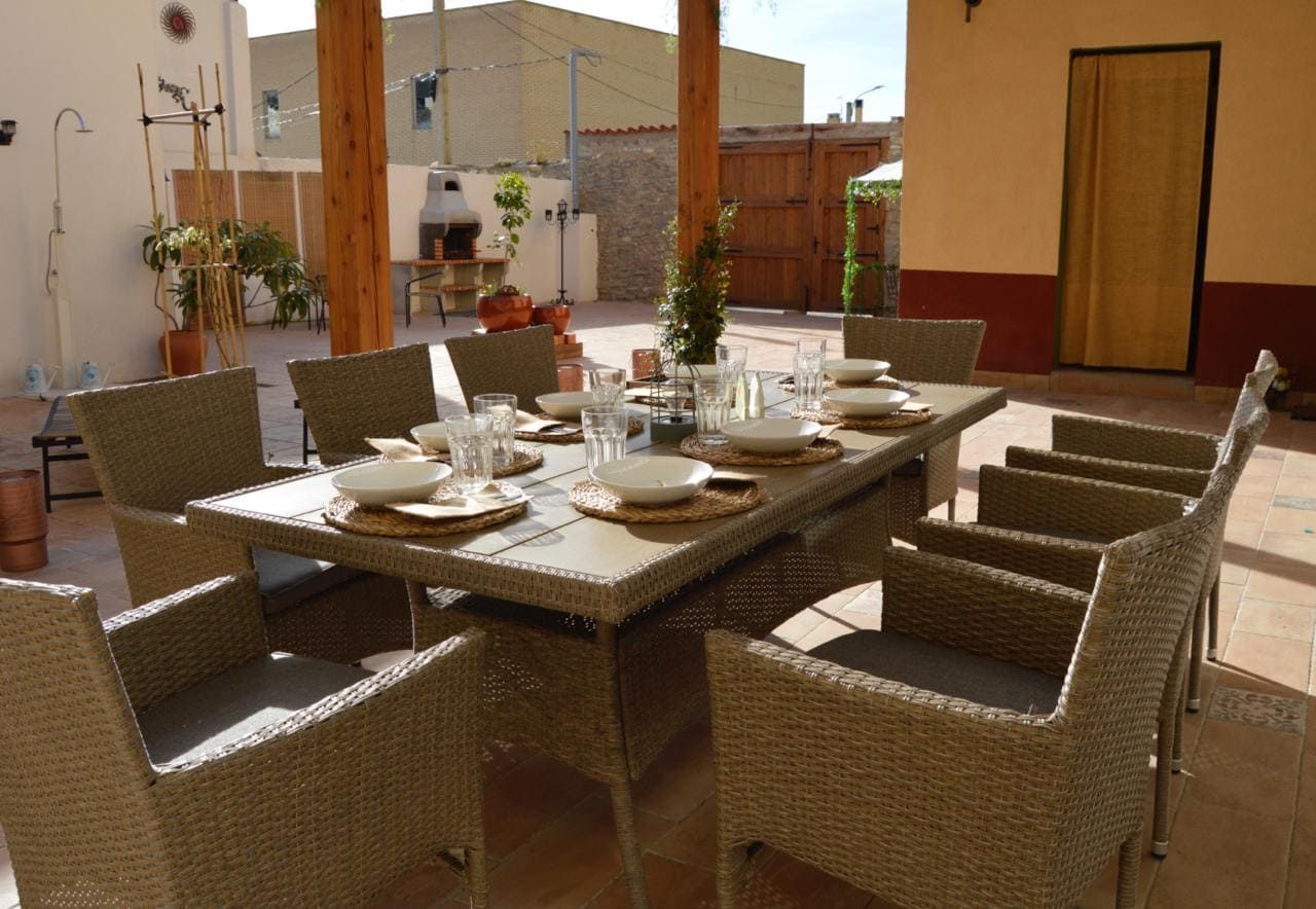 Un patio con una mesa y sillas y platos encima.