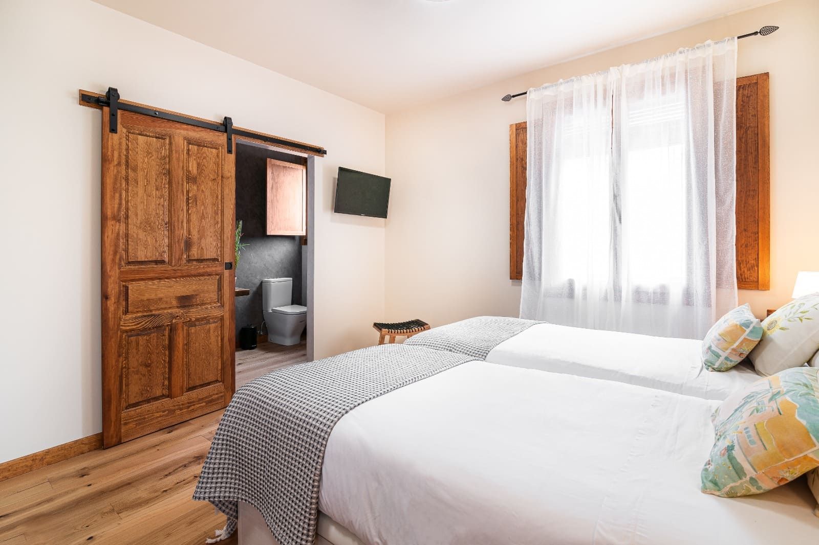 Un dormitorio con dos camas y una puerta corrediza tipo granero que conduce a un baño.