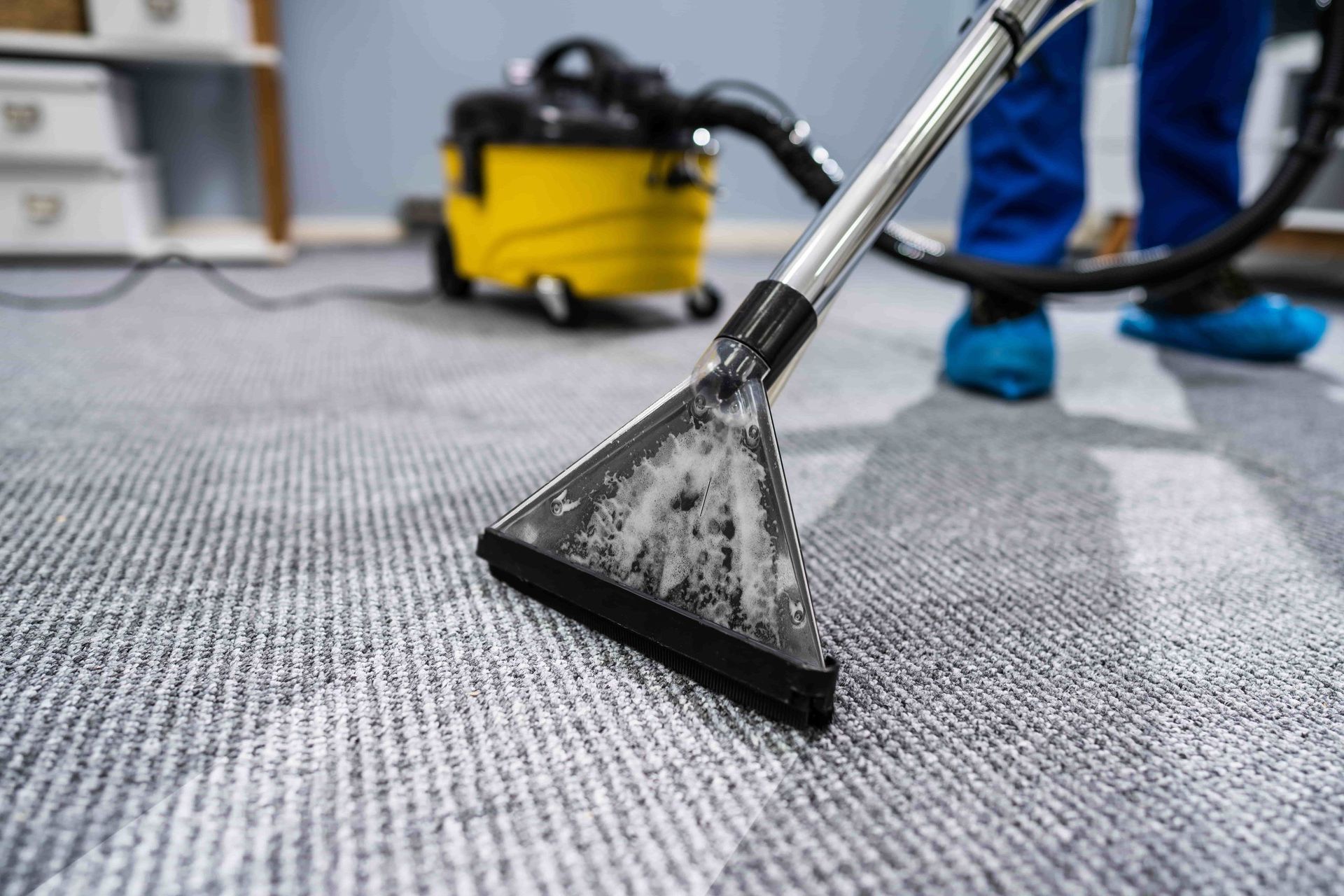 Une personne nettoie un tapis avec un aspirateur - KO Nettoyages Sàrl