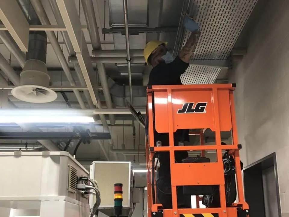 Un homme travaille sur un élévateur JLG dans un immeuble- KO Nettoyages Sàrl
