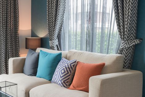 A living room with a chair , lamp , and curtains.