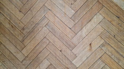 A man is installing a wooden floor in a living room.