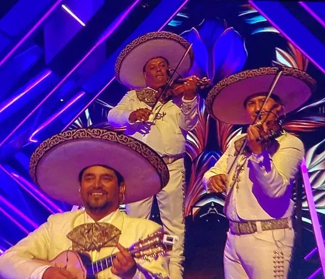 Un grupo de mariachis tocan violines y guitarras.