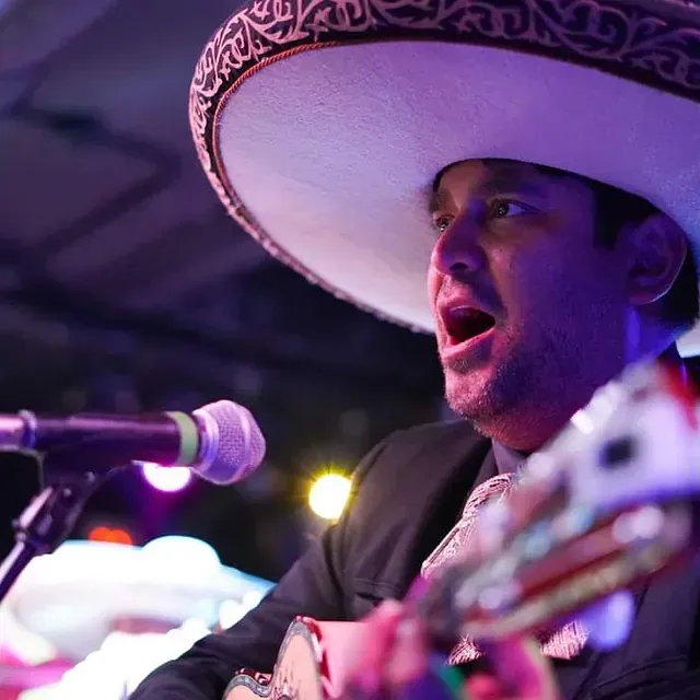 Un hombre que lleva un sombrero está cantando en un micrófono.