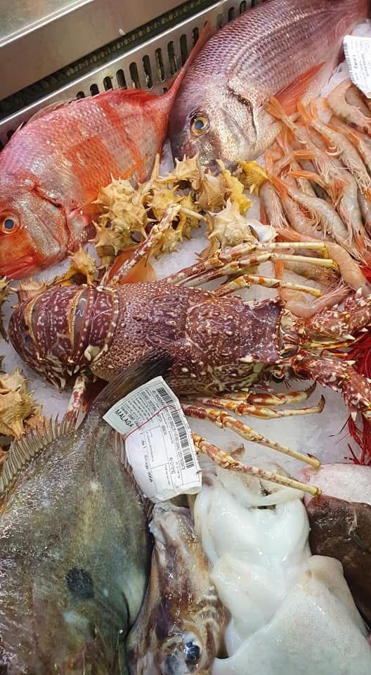 Un montón de diferentes tipos de peces están sentados sobre una mesa.
