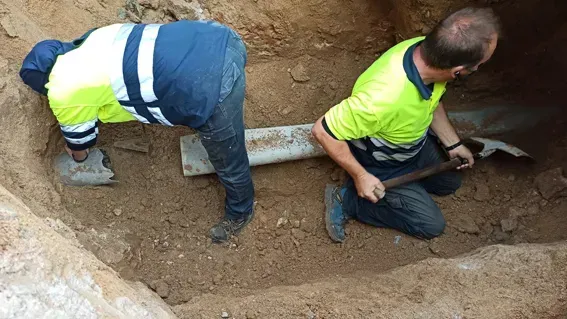 Dos hombres están arrodillados en un agujero con palas.