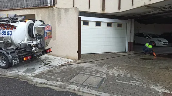 Un hombre está trabajando en una tapa de alcantarilla frente a una puerta de garaje.