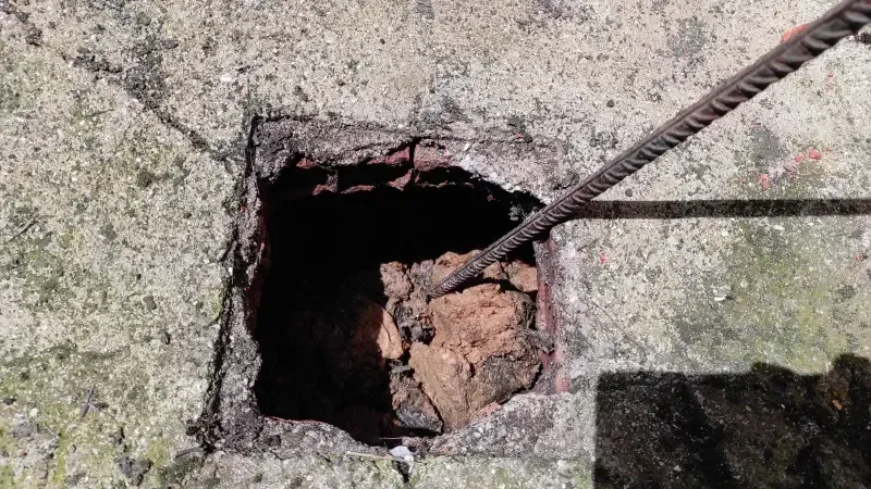 Un agujero en una pared de hormigón con una cuerda que sobresale de él.