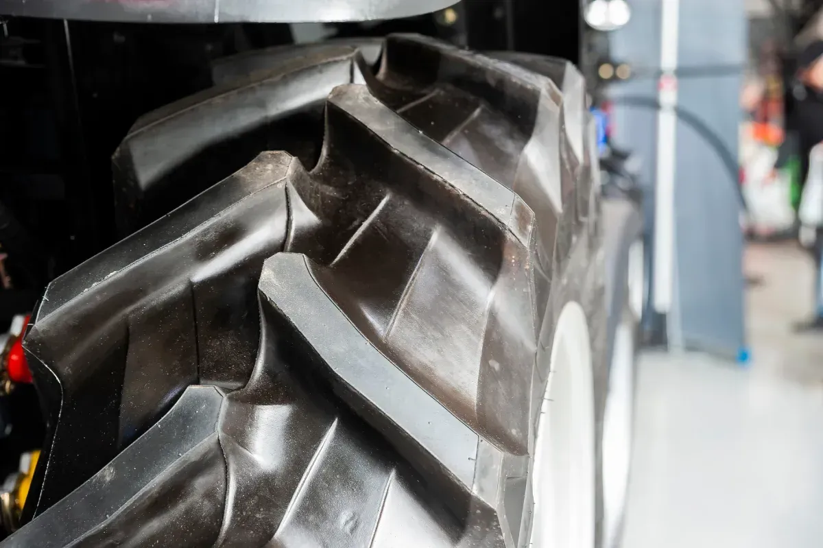 Primer plano de un neumático de tractor grande con bandas de rodadura gruesas, probablemente para trabajos agrícolas.