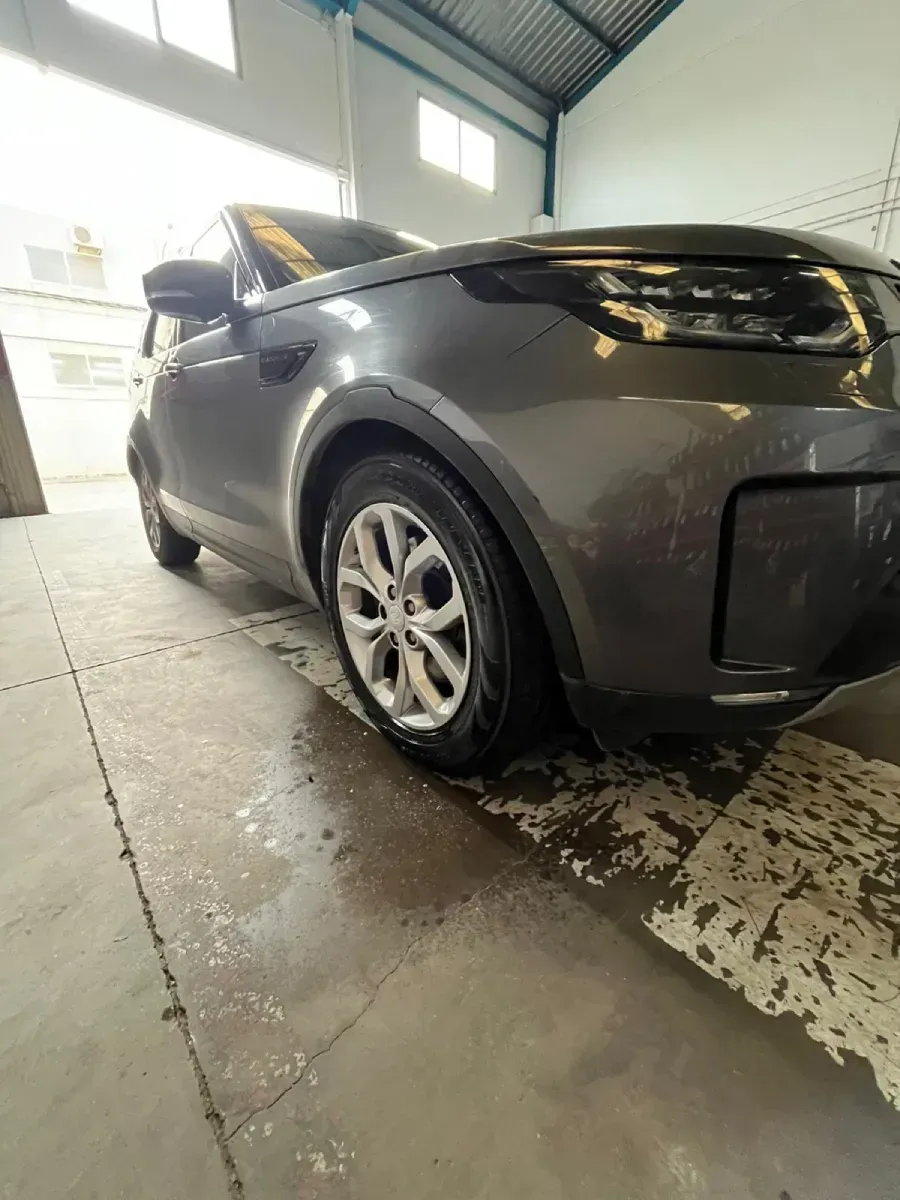 Coche Land Rover Discovery gris lavándose en un garaje con el suelo mojado.