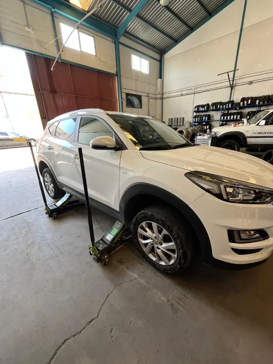 SUV blanco levantado por un gato en un taller de reparación de automóviles.