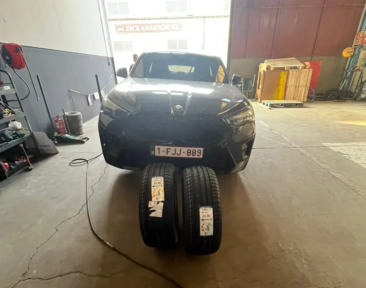 SUV negro estacionado en un garaje, con dos neumáticos nuevos delante.