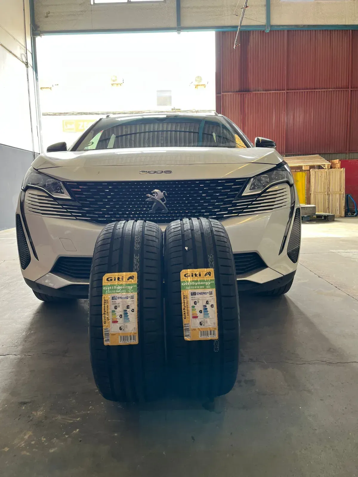 Dos neumáticos nuevos delante de un todoterreno Peugeot blanco en un garaje.