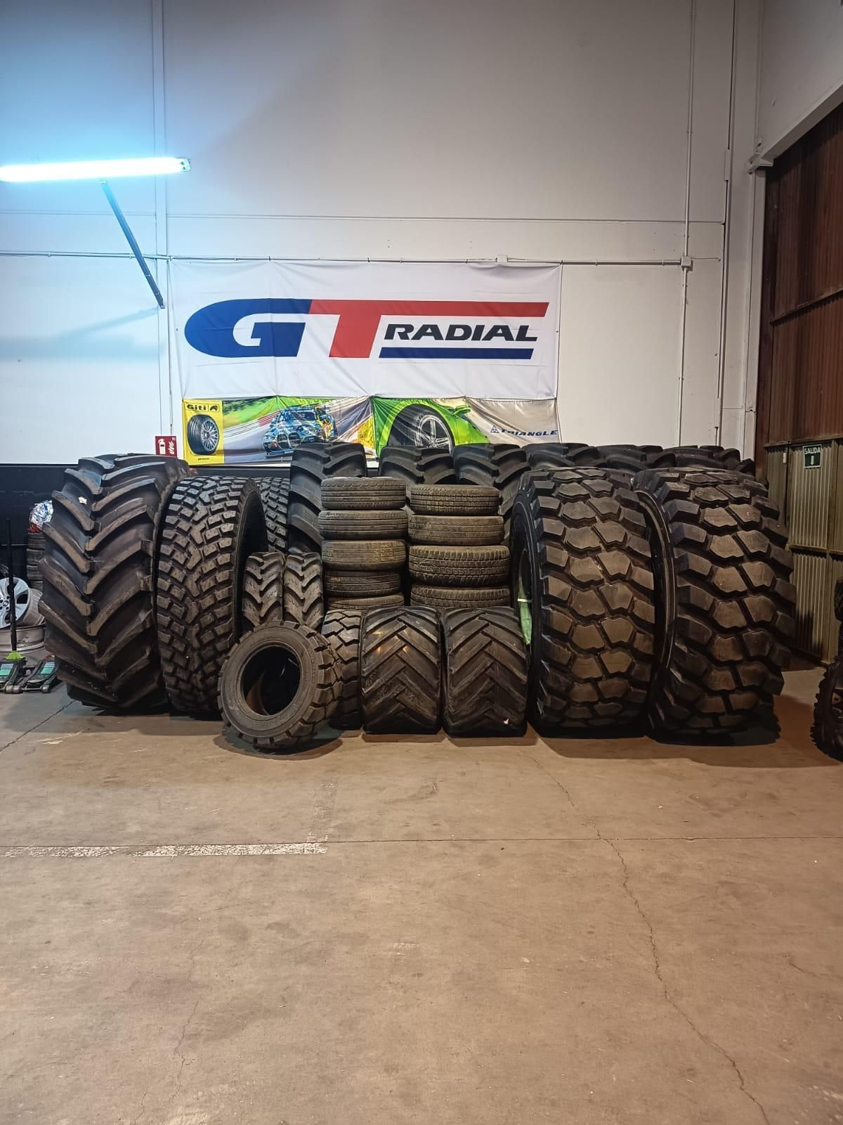 Neumático de tractor negro con dibujo de chevron sobre grava.