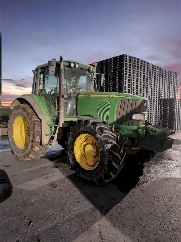 Primer plano de un neumático de tractor grande con huellas profundas, caucho negro, montado sobre una rueda plateada.