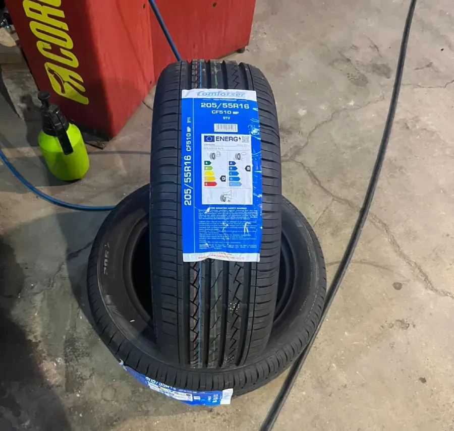 Dos neumáticos de automóvil negros, uno nuevo en la parte superior, sobre el piso de concreto de un garaje