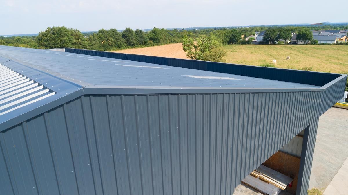 Eine Person benutzt einen Winkelschleifer an grünem Wellblech. 