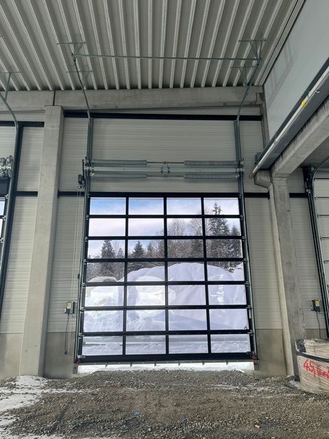 Industriegarage mit großem, verglastem Rolltor, draußen ist Schnee zu sehen.