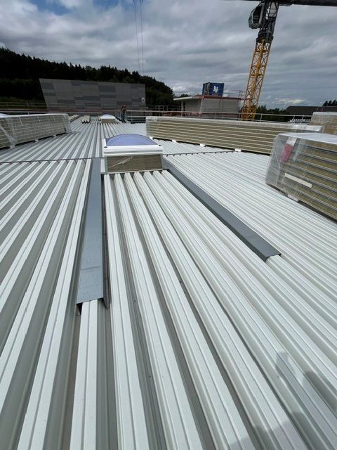 Wellblechdach auf einer Baustelle mit Kran und Tribüne im Hintergrund
