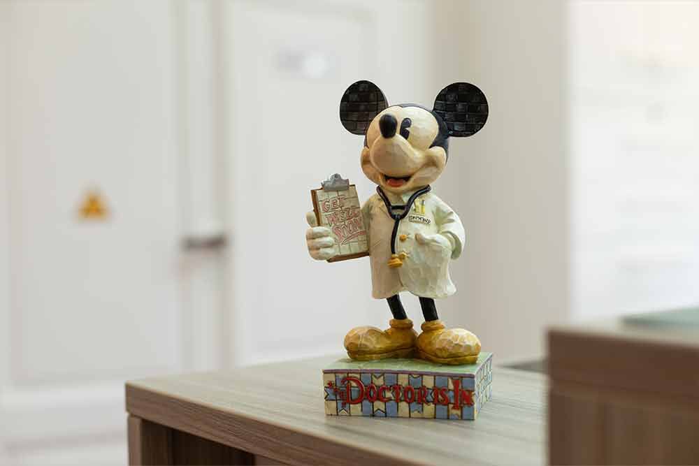 Auf einem Tisch sitzt eine Mickey Mouse-Statue, die als Arzt verkleidet ist.