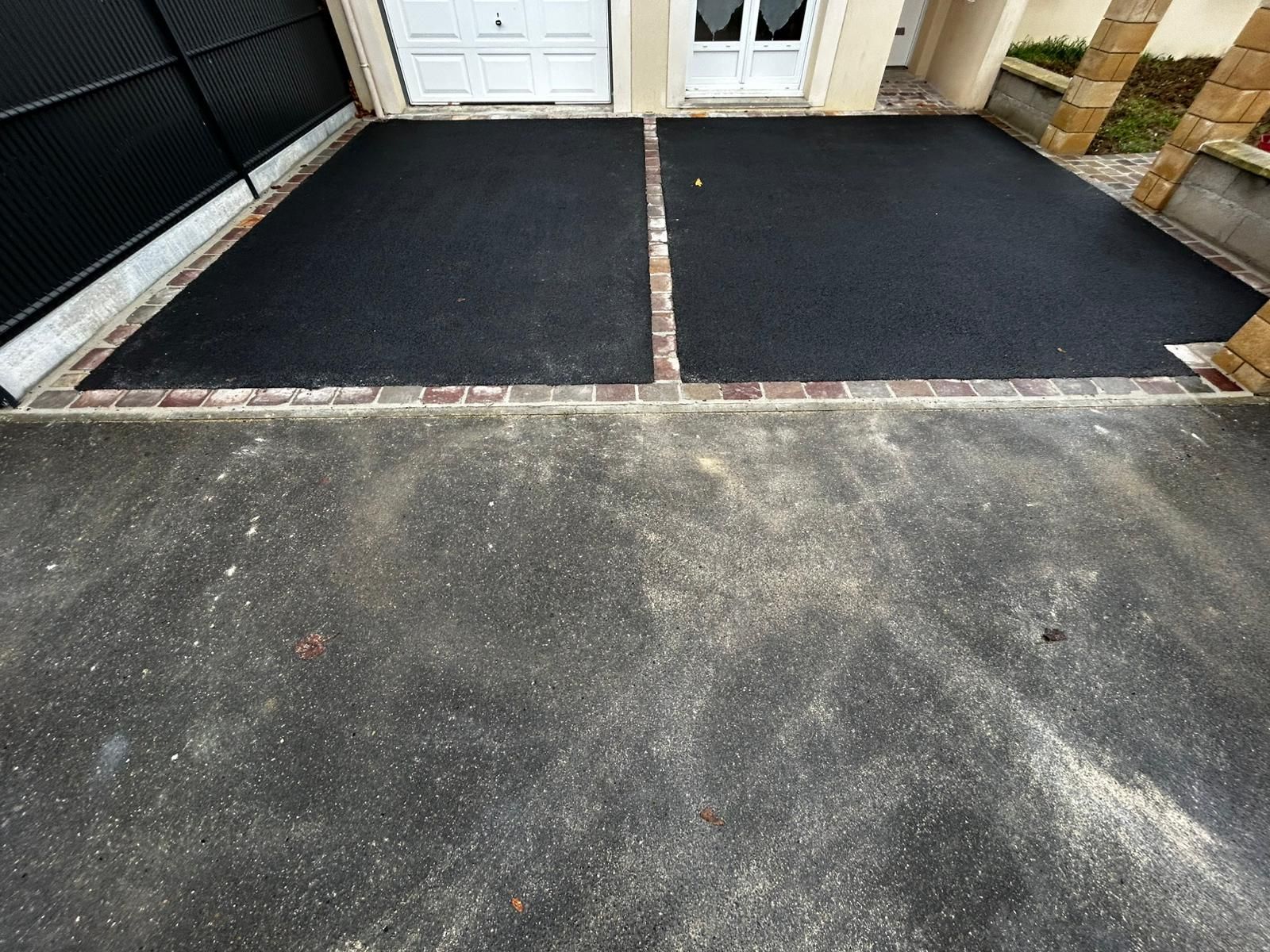 Allée nouvellement pavée de dalles rectangulaires grises devant une maison en pierre.