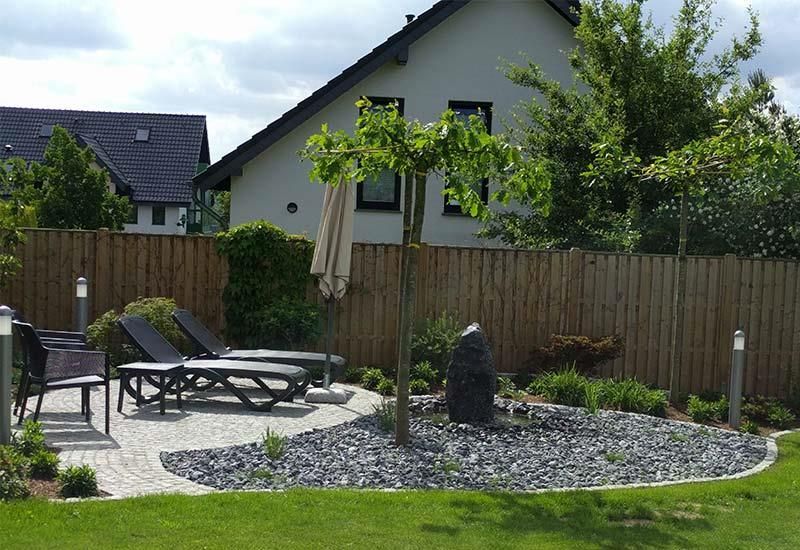 Ein Haus mit einem Holzzaun und Gartenstühlen davor