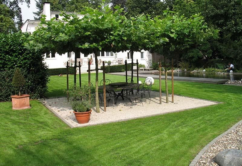 Ein Garten mit einem Tisch und Stühlen unter einem Baum