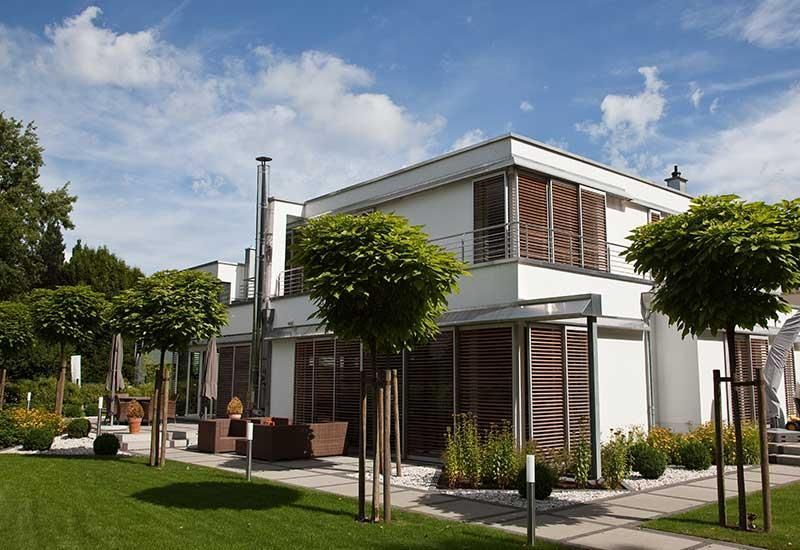 Ein weißes Haus mit vielen Fenstern und Bäumen davor