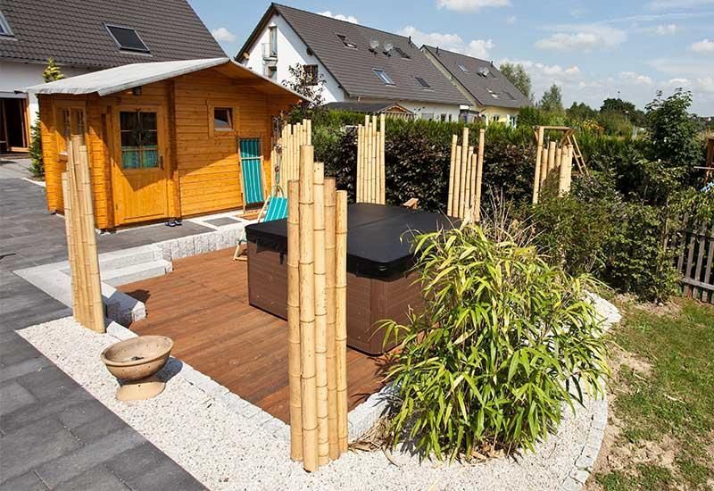 Ein Whirlpool steht auf einem Holzdeck in einem Hinterhof