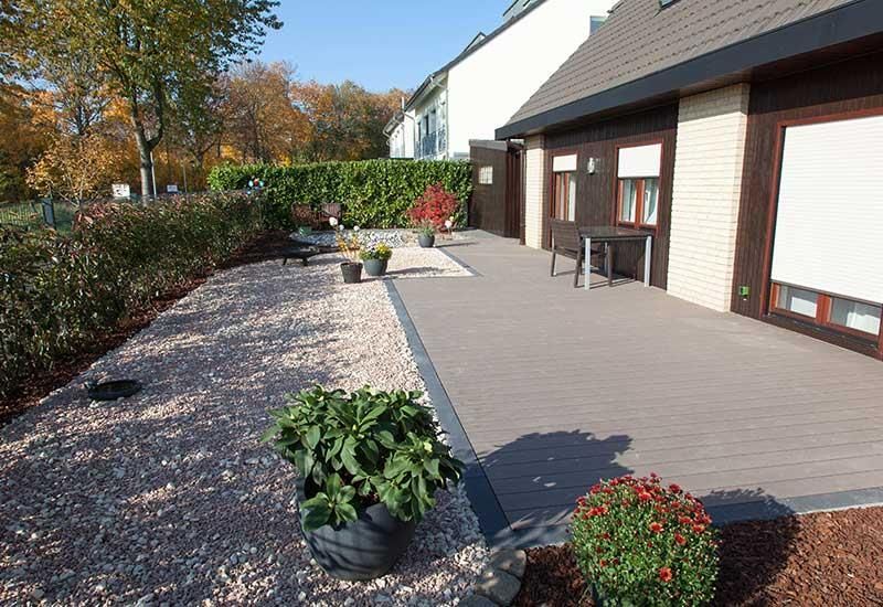 Ein Haus mit einer Terrasse und Blumen davor