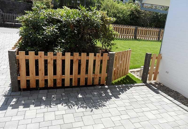 Ein Holzzaun umgibt einen Busch in einem Hof