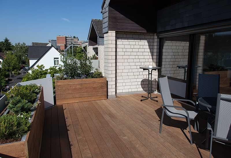 Eine Holzterrasse mit Stühlen und einem Tisch vor einem Backsteingebäude