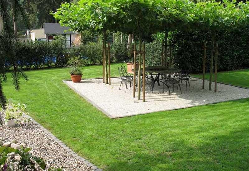 Ein Garten mit Tisch und Stühlen unter einem Baumdach