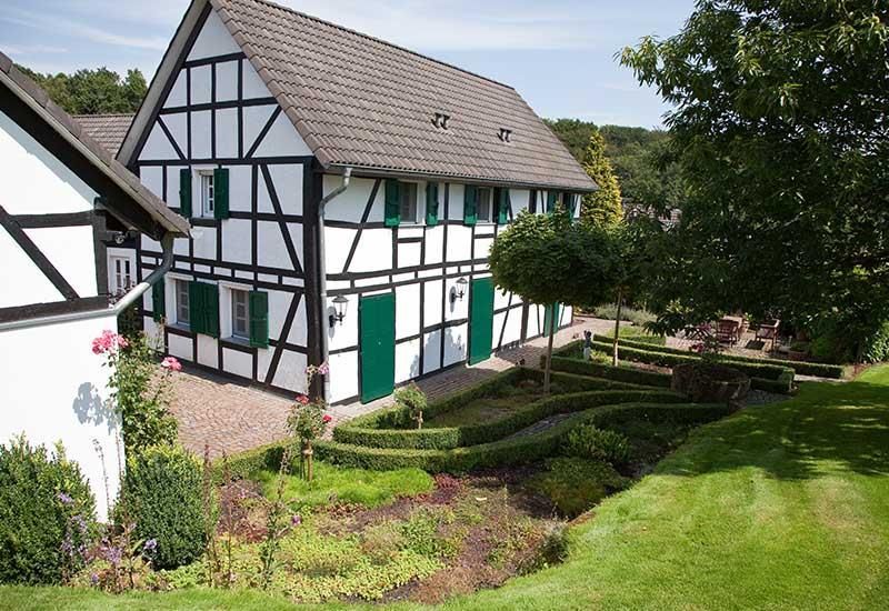 Ein schwarz-weißes Haus mit grünen Türen und Fensterläden