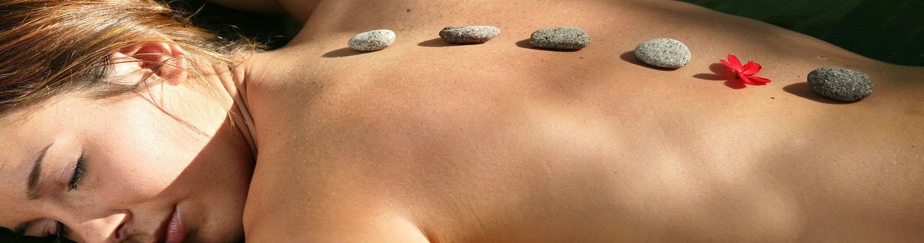 Una mujer está acostada con piedras en la espalda.