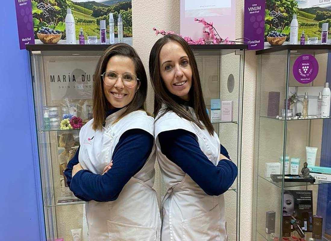 Dos mujeres están paradas espalda con espalda frente a una vitrina.