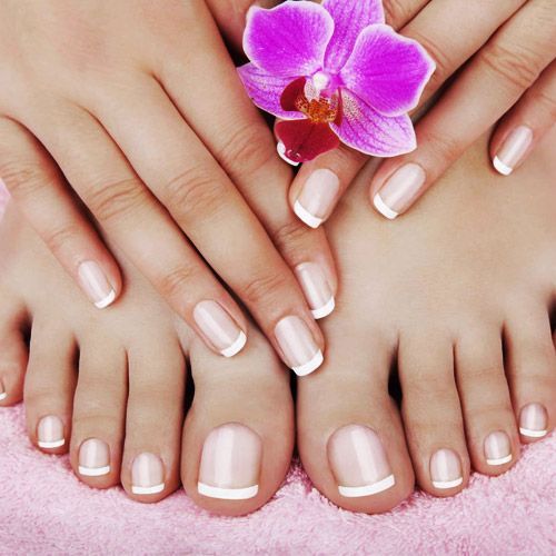 Un primer plano de las uñas y los pies de una mujer con una flor morada.
