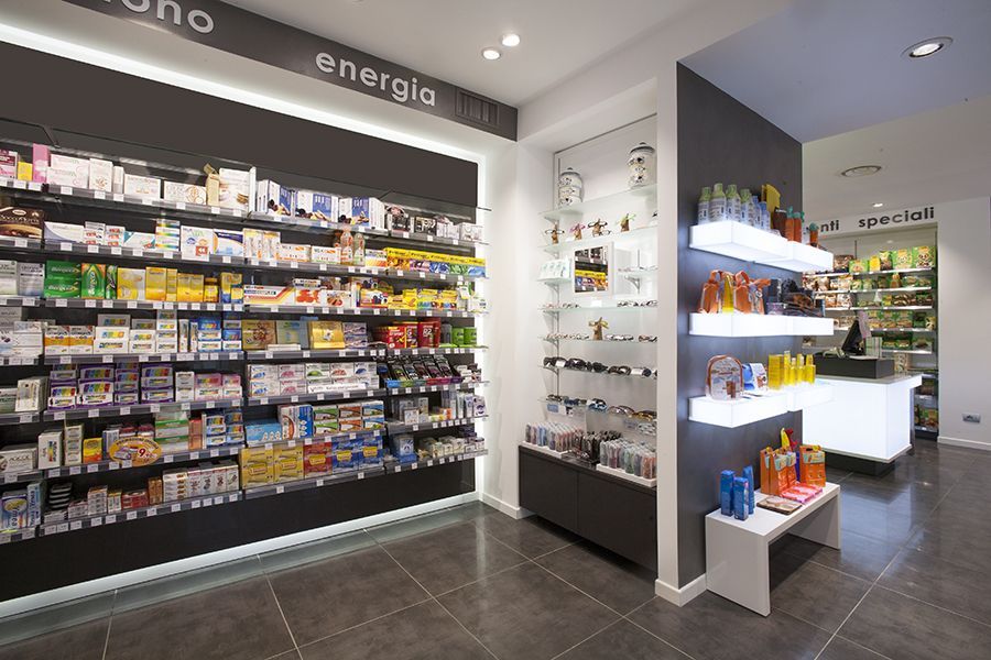 Interno luminoso della farmacia, con scaffali di medicinali e prodotti per la cura della pelle su un pavimento di piastrelle scure