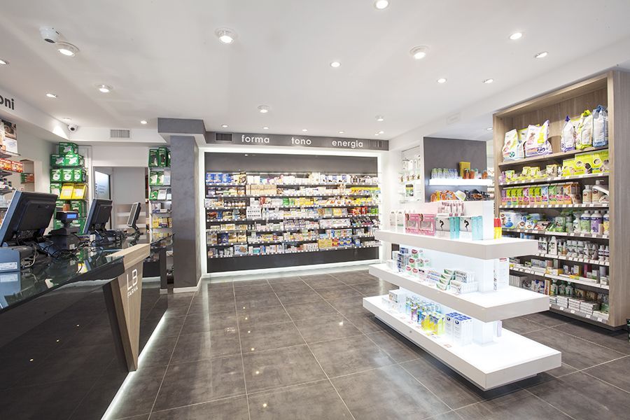 Interno luminoso della farmacia, con scaffali pieni di prodotti e un bancone cassa