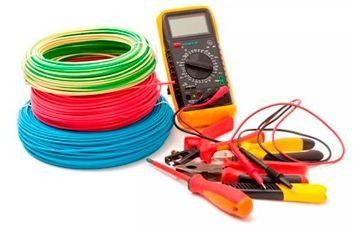 Una pila de cables, un multímetro, unos alicates y un destornillador sobre un fondo blanco.