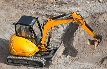 Una excavadora amarilla está cavando un hoyo en la tierra.