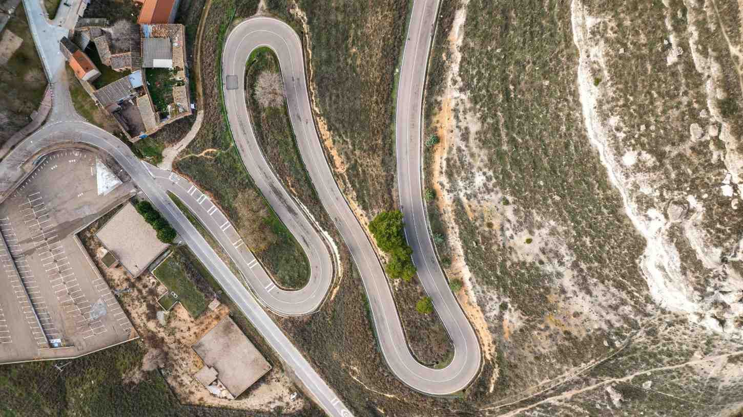 Vista aérea de una carretera sinuosa con curvas cerradas a través de un paisaje seco y montañoso.