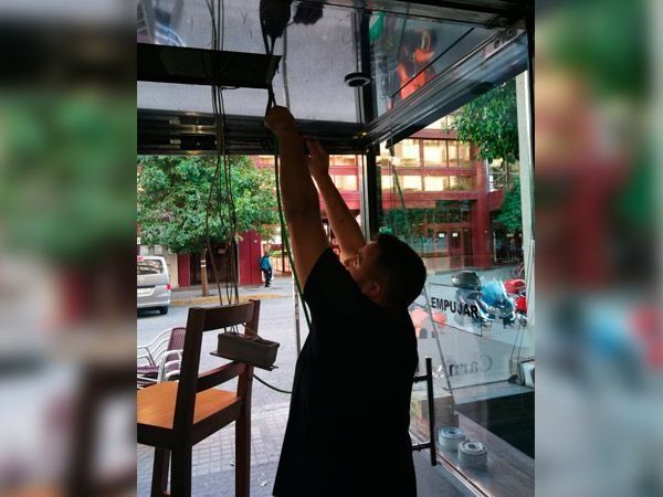 Persona alcanzando cables dentro de un puesto de comida. Vista desde el interior hacia afuera.