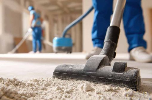 Teppichreinigung im Gange, Staubsaugerdüse auf einem beigen Teppich, Arbeiter im Hintergrund