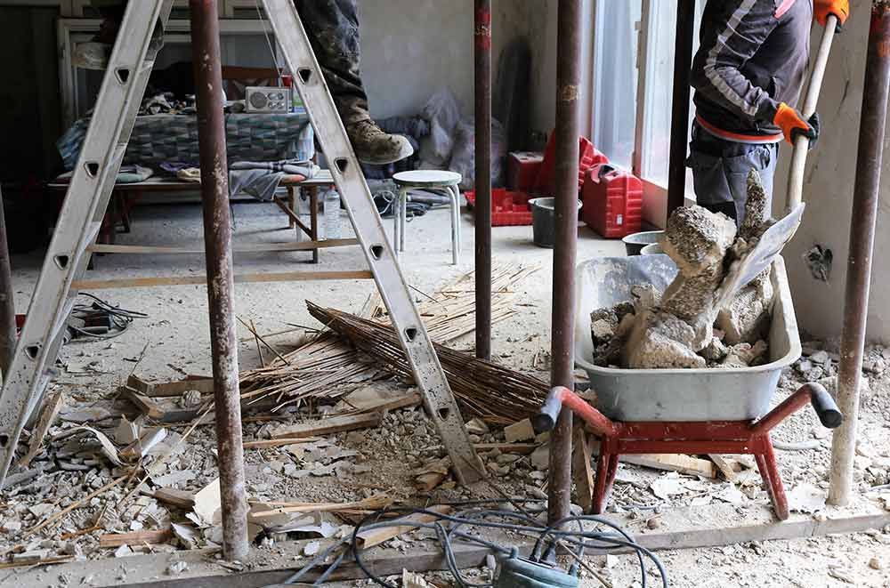 Auf einer Baustelle lagen Bauschutt und Gipsbruchstücke verstreut neben einer Leiter und einer Schubkarre auf dem Boden.