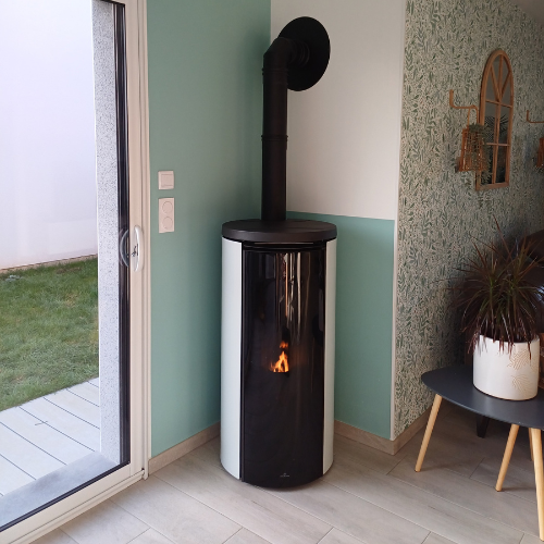 Un poêle blanc est placé dans le coin d'une pièce à côté d'une porte coulissante en verre.