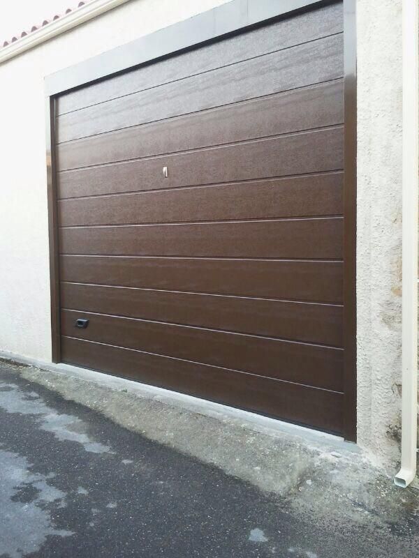Puerta de garaje de paneles horizontales de color marrón con marco de hormigón.