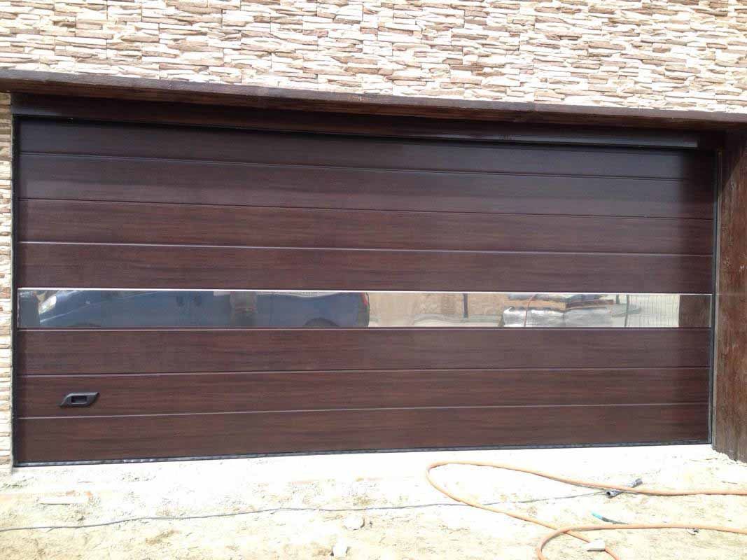 Puerta de garaje marrón con líneas horizontales y una franja plateada reflectante.
